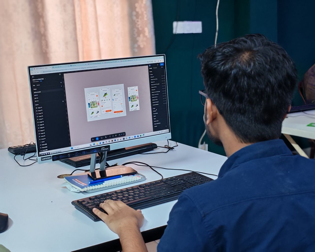 Home A young designer focused on creating user interfaces on a desktop computer in an office setting.
