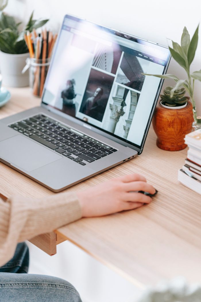 Services Crop unrecognizable distance employee browsing internet on netbook with photo gallery while sitting at desk in house on white background